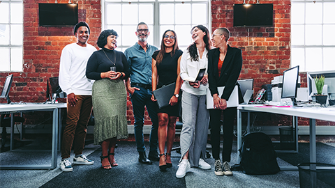 Happy group of businesspeople laughing cheerfully in a modern workplace