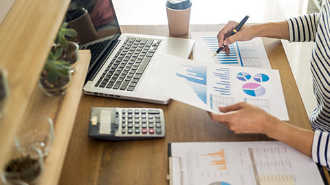 woman working on a laptop tablet and graph data documents on his desk in home office