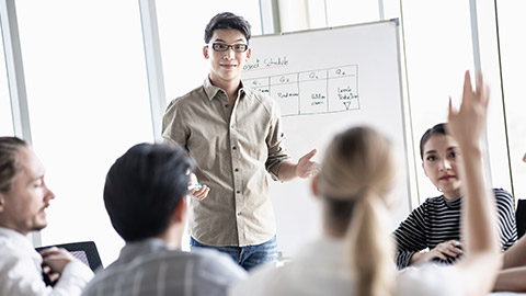 young Asian man creative leader talking to happy diverse business people group during meeting