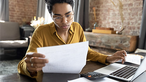 woman in eyeglasses looking through paper documents