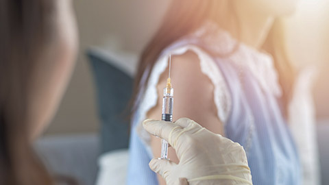 Woman having vaccination for influenza or flu shot or HPV prevention with syringe by nurse