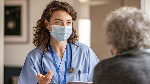 Doctor wearing safety protective mask supporting and cheering up senior patient