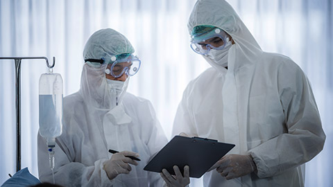 professional doctors in the full protective suits and surgical masks are examining the infected patient in the hospital control area