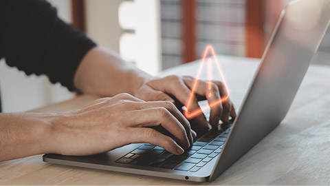 a man using computer laptop with triangle caution warning sign