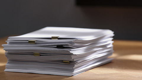 Stack of blank paper with binder clips on wooden table indoors