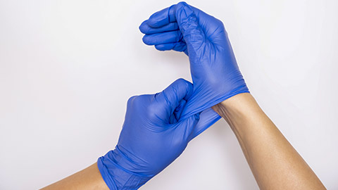 nurse putting on blue nitrile surgical gloves