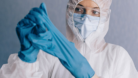 Female doctor takes off protective gloves after finishing work