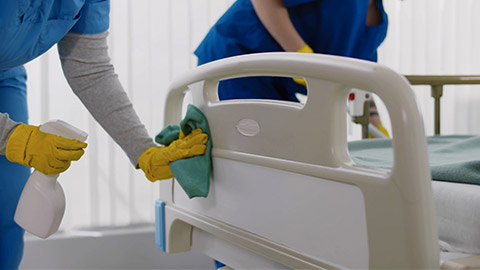 Nurses in uniform cleaning furniture in empty clinic room