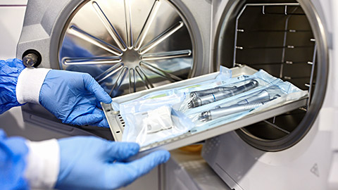 Nurse putting instruments in special craft paper bags into autoclave for processing