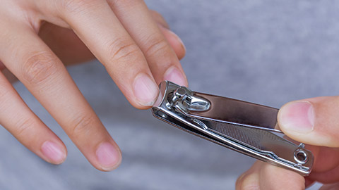 woman trimming nails with a nail clipper