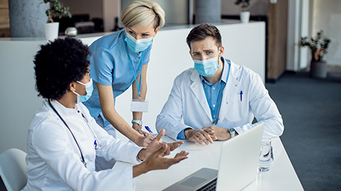 healthcare workers cooperating while using laptop on a meeting at medical clinic