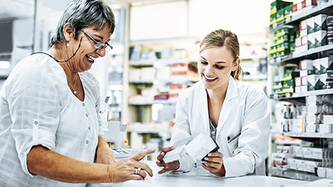 Pharmacist explaining medicines to a happy senior customer