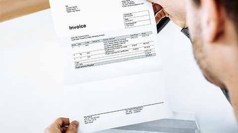 Overhead of a man reading an invoice on paper