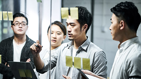 Young man drawing diagram on glass during a meeting