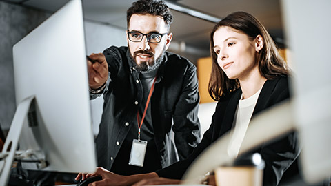 A man pointing at the computer screen, a woman typing on the computer