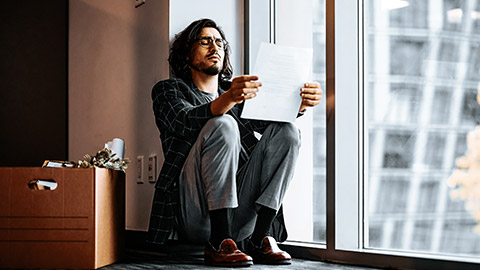 Sad man reading a document after being fired from the job