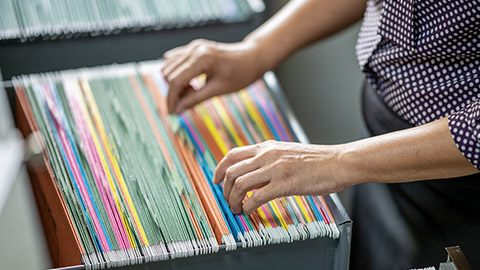 Woman's hand searching for documents at the filing cabinet