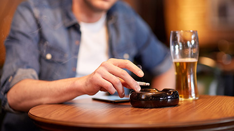 close up of man drinking beer, smoking cigarette