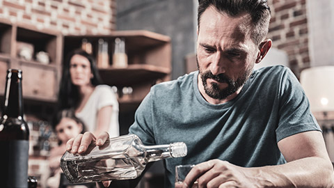 An alcoholic sitting at a table drinking