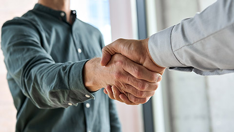 Two happy diverse professional business men executive leaders shaking hands at office meeting