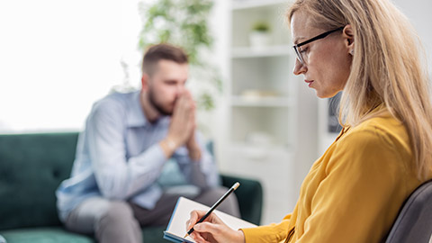 Woman medical doctor psychologist making notes while listening to male patient