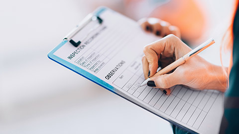 A person writing notes on a clipboard