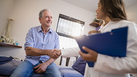 female therapist and senior male patient shaking hands