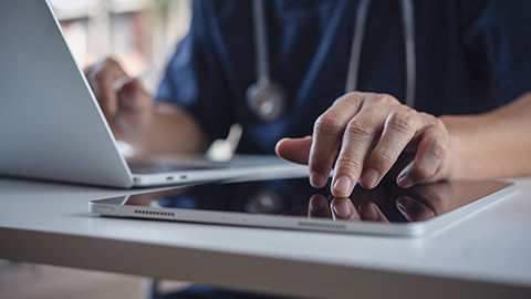 Close up of doctor, surgeon using digital tablet and laptop computer