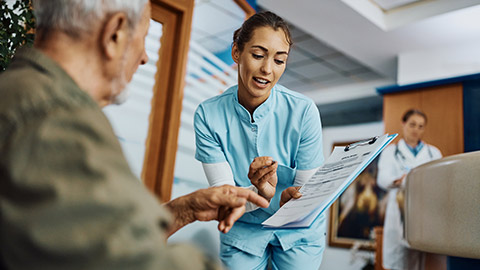 nurse and senior patient talking while going through his medical data at the clinic