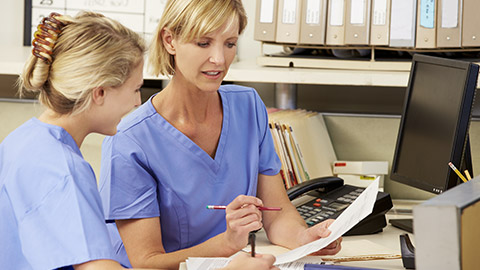 Two Nurses Working At Nurses Station