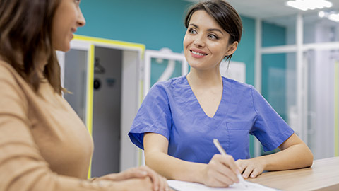 young woman holding pen over medical document and consulting a woman in clinic