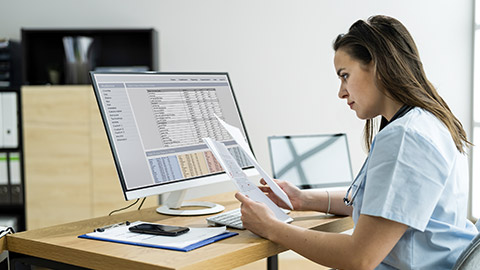 lady working on medical records using a computer at her desk