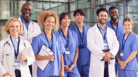 Portrait Of Smiling Medical Team Standing In Modern Hospital Building