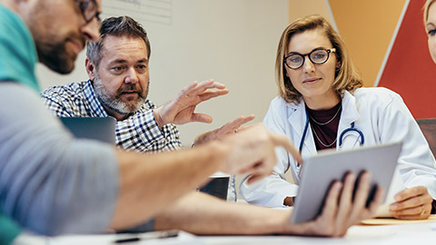 healthcare workers with digital tablet meeting in hospital boardroom