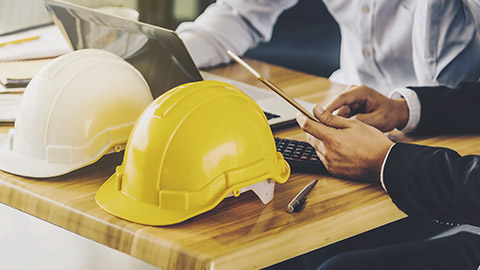 white,yellow hard safety helmet hat for safety project of workmen on a wooden desk