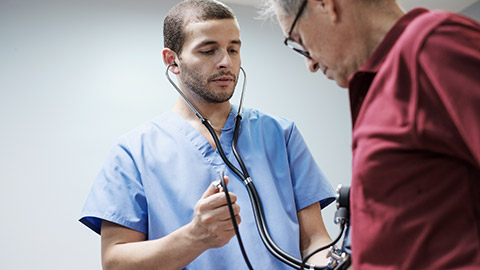 Nurse and Doctor in a Clinic Measure an Hispanic Old Man Blood Pressure