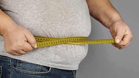 A man measures his fat belly with a measuring tape