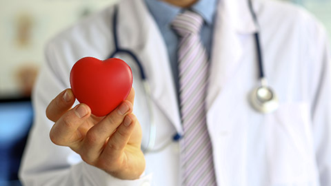 doctor holding a red heart-shaped symbol