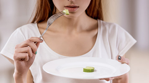 Thin girl holding an almost empty plate standing