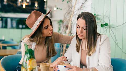 young caucasian woman comforts her friend in cafe during coffee break