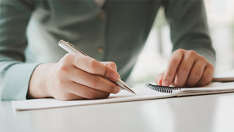 Business women write on notepad with pen to calculate financial statements within the office