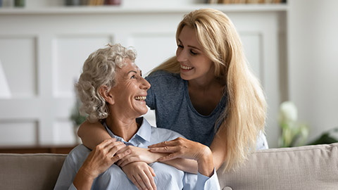 Overjoyed senior 60s mother and adult daughter relax together in living room