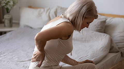 woman suffering from backache after sleep, rubbing stiff muscles