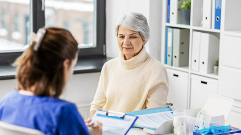 medicine, health and vaccination concept - doctor with clipboard and senior woman at hospital