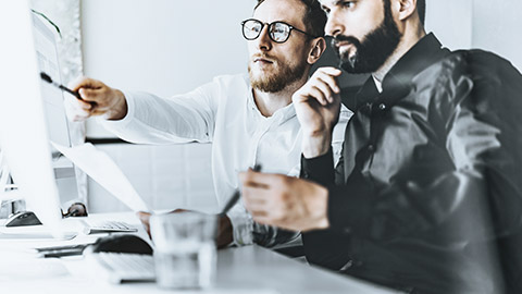 A man pointing to a screen for his colleague