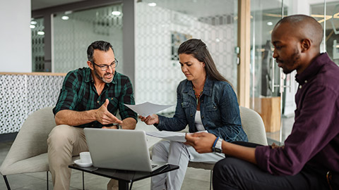 Casual meeting of smiling diverse business team analyzing financial data