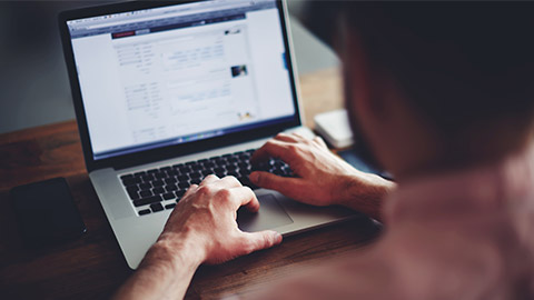 Cropped image of a young man working on his laptop in a coffee shop