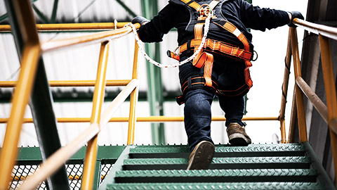 A construction worker putting in a safety harness on rails