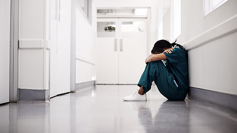 A stressed out nurse sitting on the floor