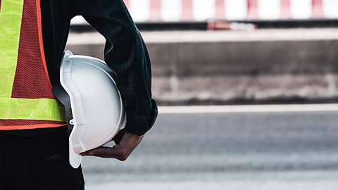 Aperson holding a protective construction hat